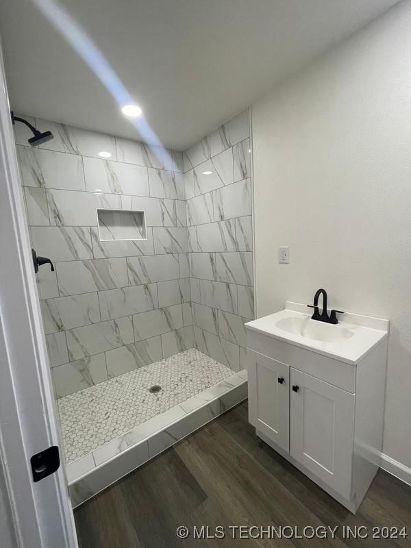 bathroom with a tile shower, hardwood / wood-style floors, and vanity