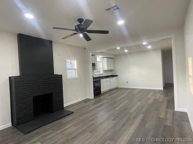 unfurnished living room featuring ceiling fan, dark hardwood / wood-style floors, and a brick fireplace