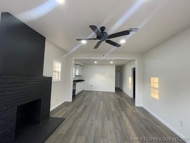 unfurnished living room featuring ceiling fan, a fireplace, and dark wood-type flooring