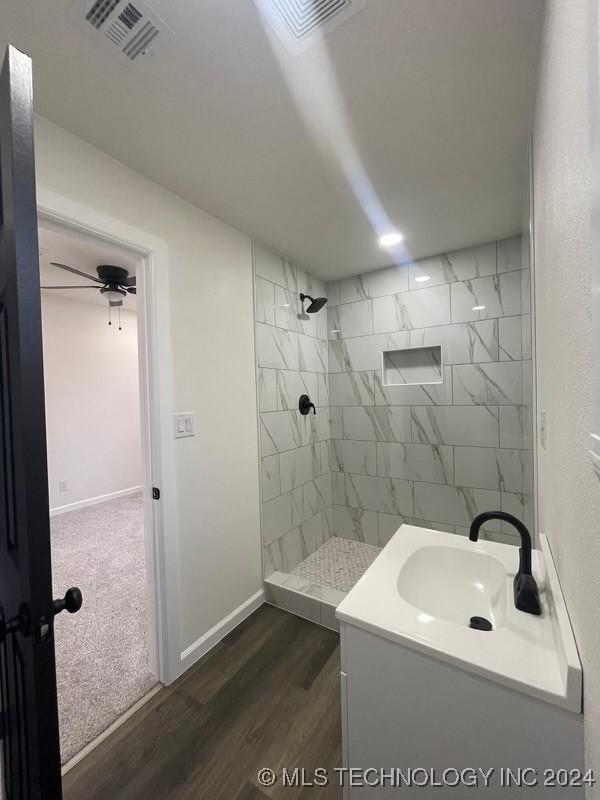 bathroom featuring hardwood / wood-style floors, vanity, and tiled shower