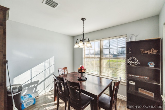 dining space with hardwood / wood-style floors and a notable chandelier