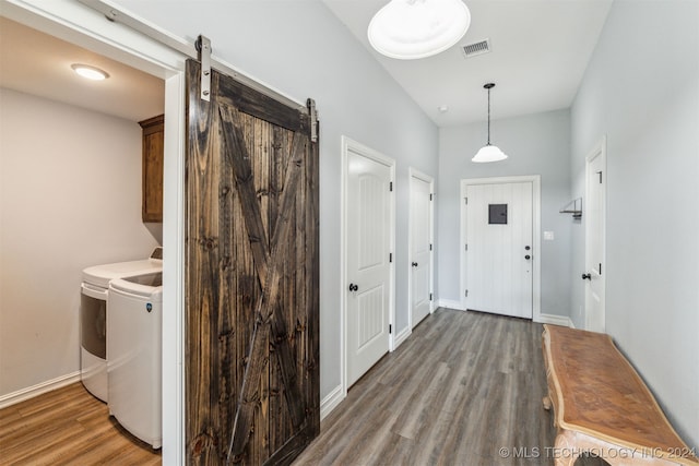 interior space featuring a barn door, separate washer and dryer, hardwood / wood-style floors, and cabinets