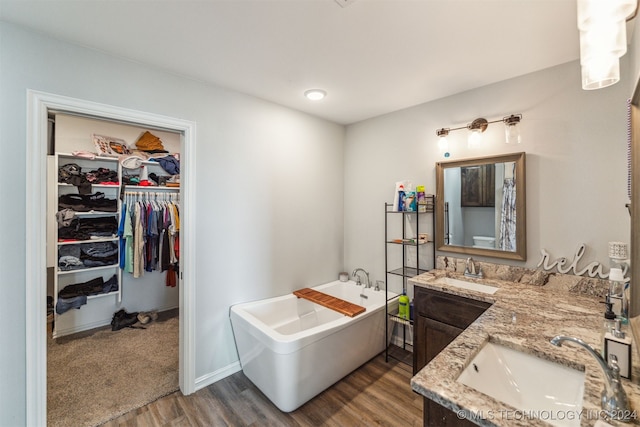 bathroom with hardwood / wood-style floors, vanity, and a tub