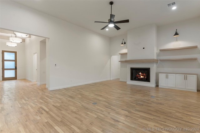 unfurnished living room featuring ceiling fan, light hardwood / wood-style floors, and a fireplace