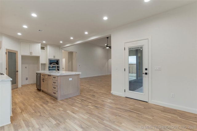 kitchen with sink, ceiling fan, light wood-type flooring, an island with sink, and white cabinetry