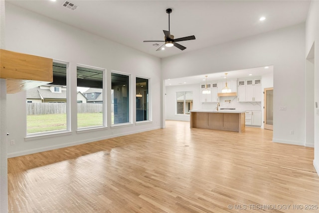 unfurnished living room with a wealth of natural light, visible vents, recessed lighting, and ceiling fan
