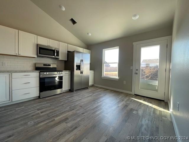 kitchen with appliances with stainless steel finishes, backsplash, dark wood-type flooring, white cabinets, and lofted ceiling