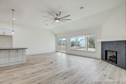 unfurnished living room with a fireplace, light wood-type flooring, ceiling fan, and lofted ceiling