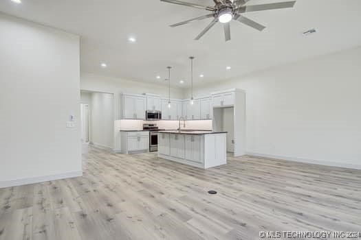 kitchen featuring appliances with stainless steel finishes, light hardwood / wood-style flooring, white cabinets, a kitchen island, and hanging light fixtures