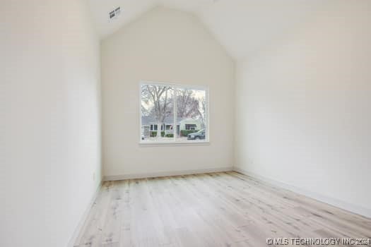 unfurnished room with light hardwood / wood-style floors and lofted ceiling