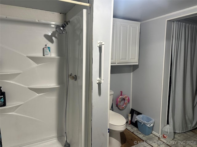 bathroom featuring tile patterned flooring, toilet, and a shower