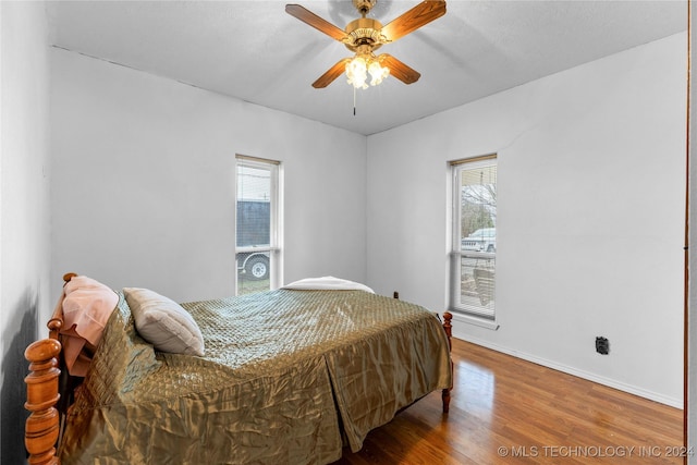 bedroom with multiple windows, ceiling fan, and hardwood / wood-style flooring