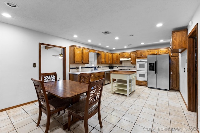 kitchen featuring a center island, ceiling fan, tasteful backsplash, light tile patterned flooring, and stainless steel appliances