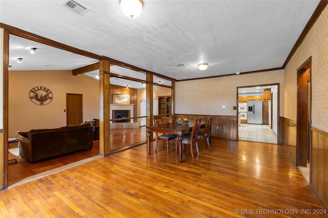 dining area with vaulted ceiling with beams, light hardwood / wood-style floors, crown molding, and a textured ceiling