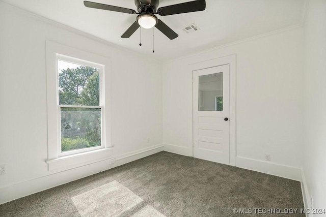 spare room featuring dark colored carpet, ceiling fan, and crown molding