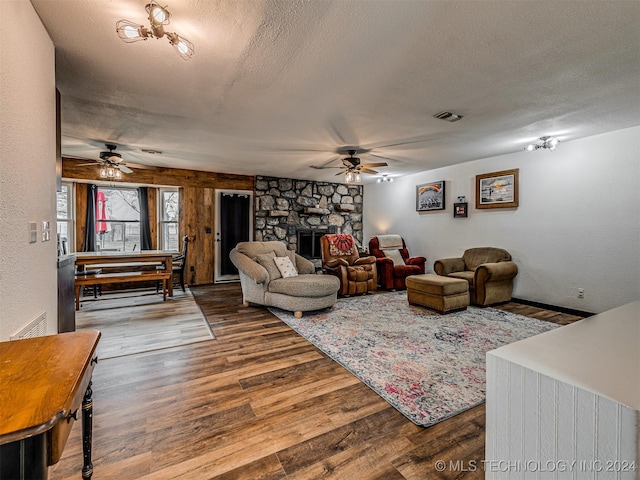 living room featuring ceiling fan, a fireplace, a textured ceiling, and hardwood / wood-style flooring