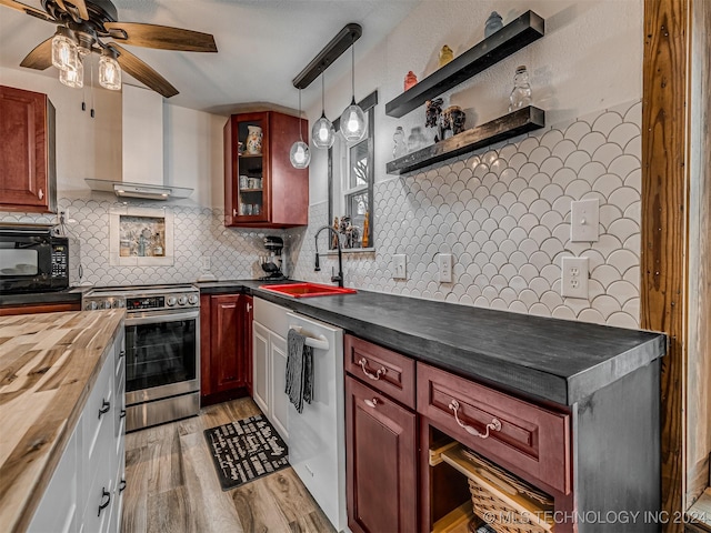 kitchen featuring backsplash, hanging light fixtures, sink, wall chimney exhaust hood, and appliances with stainless steel finishes