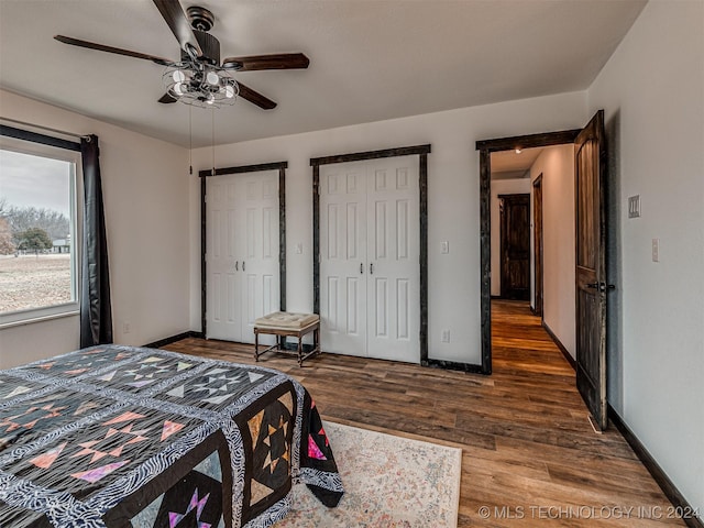 bedroom featuring multiple closets, ceiling fan, and dark hardwood / wood-style flooring