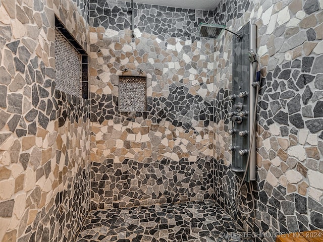 bathroom with a textured ceiling and tiled shower