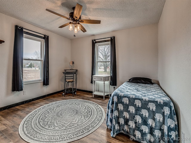 bedroom with a textured ceiling, hardwood / wood-style flooring, and ceiling fan