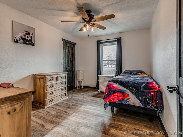 bedroom with ceiling fan, a textured ceiling, and hardwood / wood-style flooring