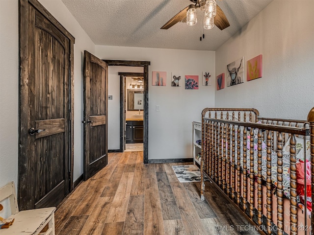 bedroom featuring a textured ceiling, hardwood / wood-style flooring, ceiling fan, and sink