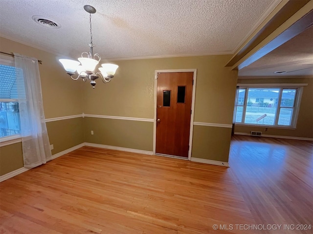 spare room with crown molding, light wood-type flooring, a textured ceiling, and an inviting chandelier