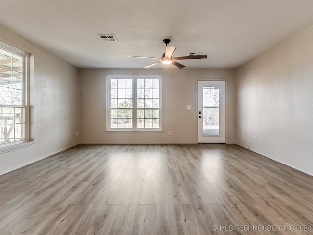 empty room with plenty of natural light, ceiling fan, and light hardwood / wood-style flooring