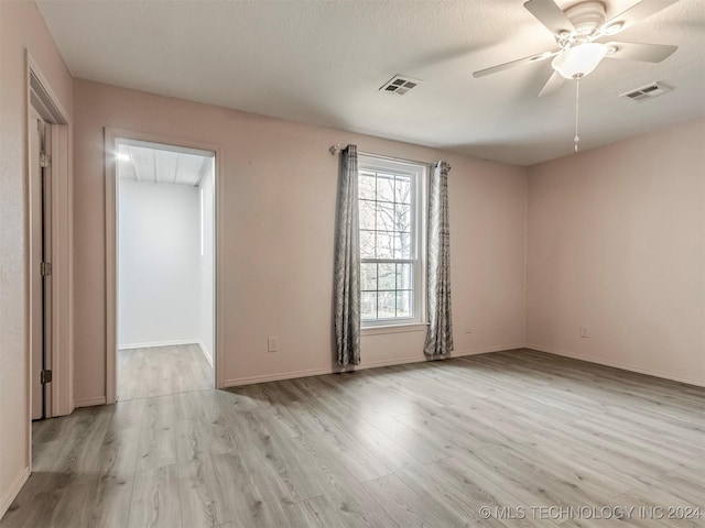 spare room with ceiling fan, light wood-type flooring, and a textured ceiling