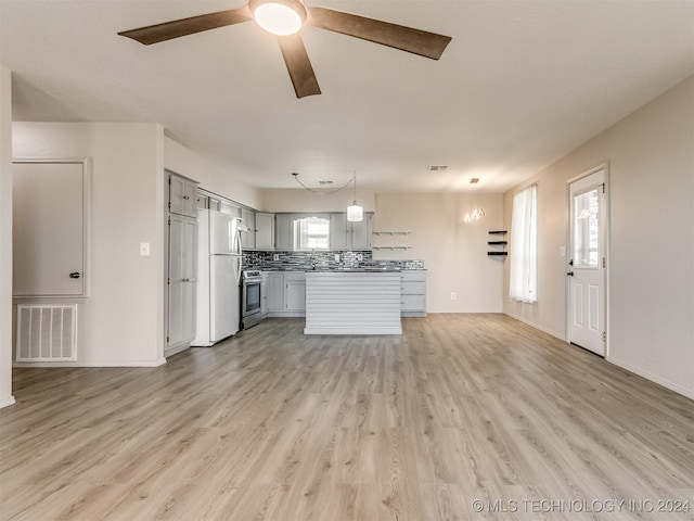 kitchen featuring gray cabinetry, stainless steel range, hanging light fixtures, backsplash, and white fridge