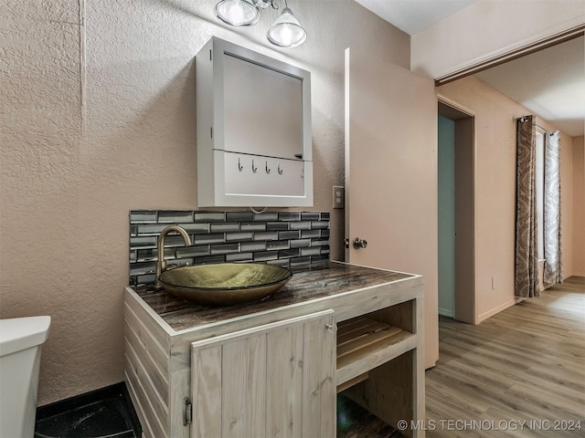 bathroom featuring tasteful backsplash, hardwood / wood-style floors, vanity, and toilet