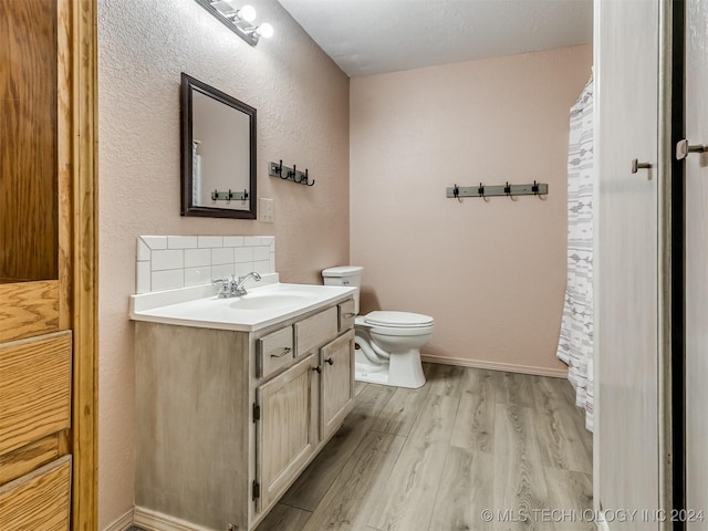 bathroom with hardwood / wood-style flooring, vanity, toilet, and tasteful backsplash