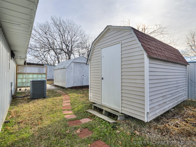 view of outdoor structure with central air condition unit and a yard