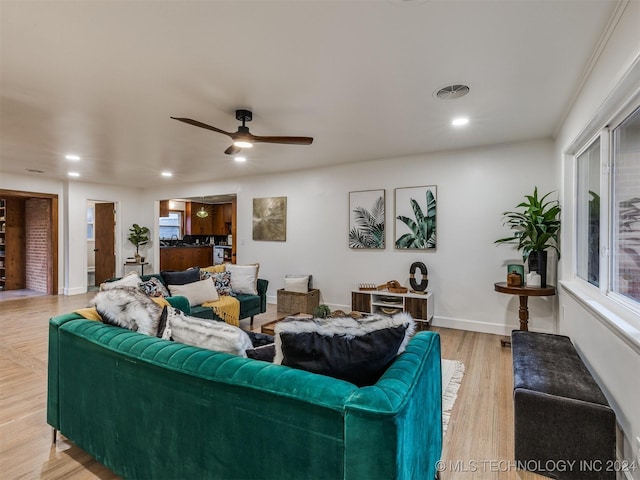 living room featuring ceiling fan, light wood-type flooring, and crown molding