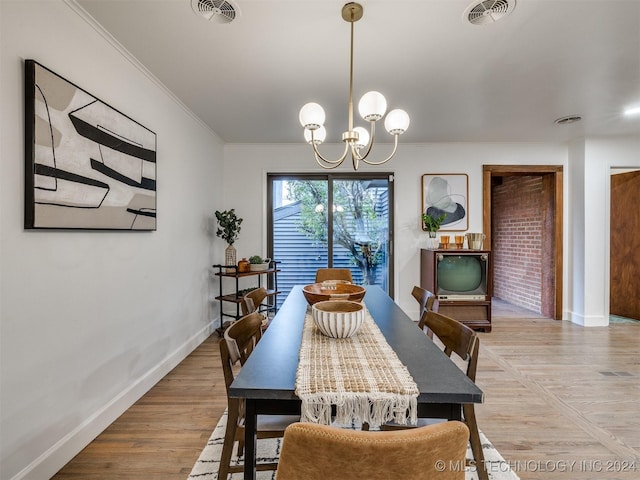 dining space featuring baseboards, light wood-type flooring, visible vents, and an inviting chandelier