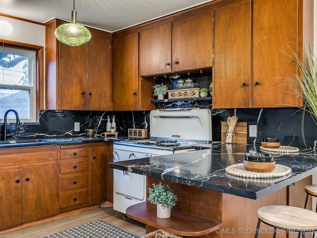 kitchen with brown cabinets, gas range gas stove, a breakfast bar area, open shelves, and a sink