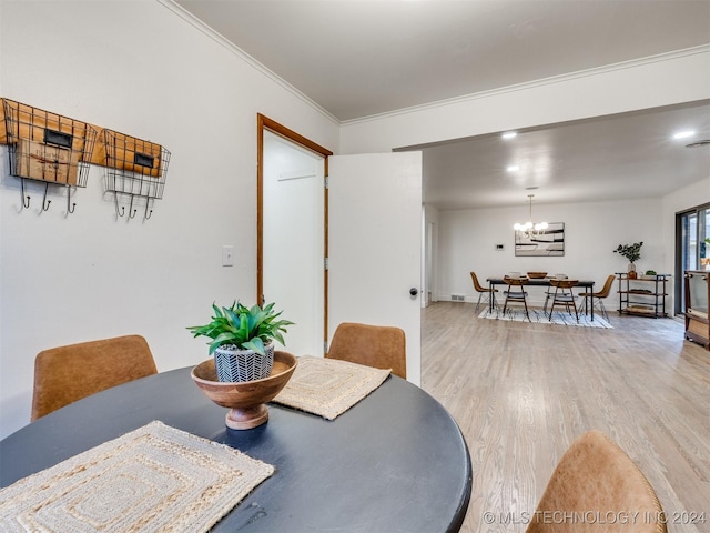 dining space with a chandelier, light wood finished floors, and ornamental molding