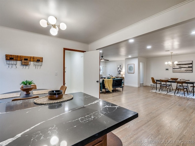 kitchen featuring baseboards, dark countertops, an inviting chandelier, crown molding, and light wood-type flooring