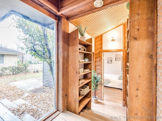 doorway with light wood finished floors and vaulted ceiling