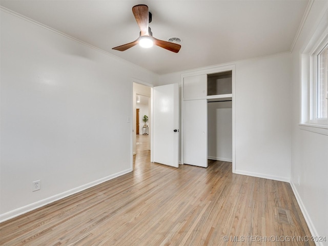 unfurnished bedroom featuring baseboards, visible vents, ornamental molding, light wood-style floors, and a closet