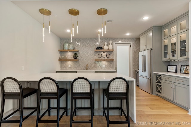 kitchen featuring decorative backsplash, pendant lighting, high end fridge, and gray cabinetry