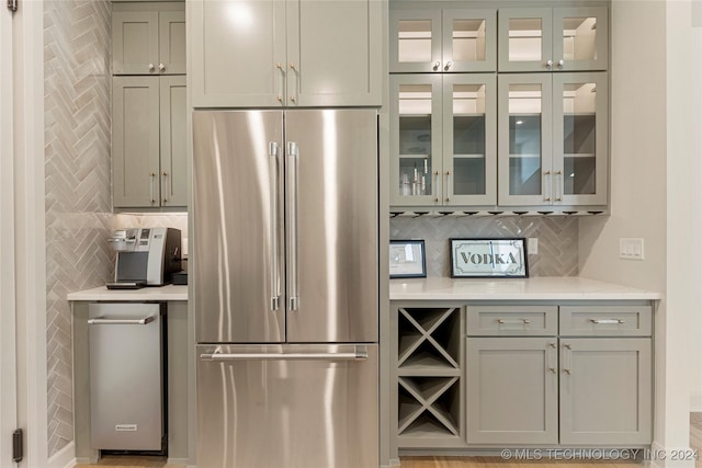 kitchen with gray cabinetry, backsplash, and stainless steel refrigerator