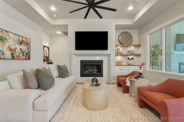 living room with ceiling fan and a tray ceiling