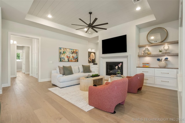 living room featuring light hardwood / wood-style flooring, a raised ceiling, ceiling fan, and wood ceiling