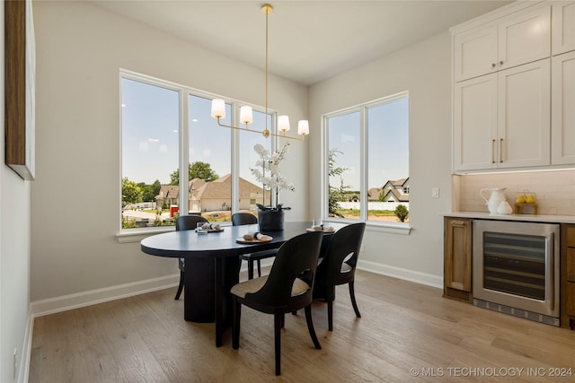 dining room featuring light hardwood / wood-style floors, beverage cooler, and a healthy amount of sunlight