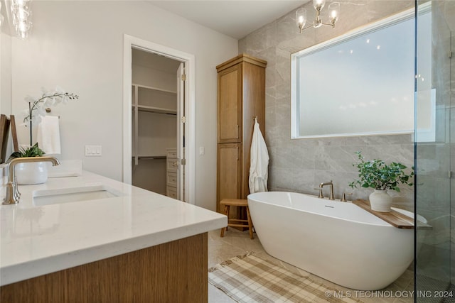 bathroom featuring tile patterned floors, vanity, shower with separate bathtub, and a notable chandelier