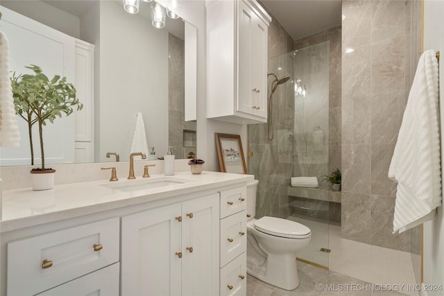 bathroom featuring tile patterned flooring, vanity, toilet, and a tile shower