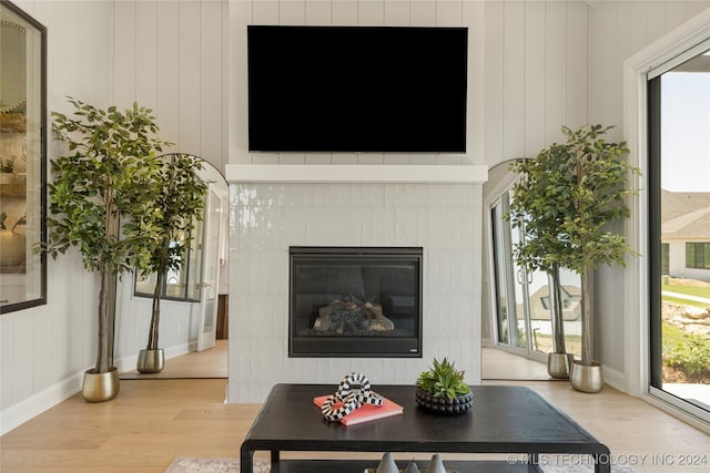 living room with a healthy amount of sunlight, light hardwood / wood-style flooring, and a tiled fireplace