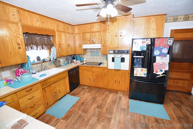 kitchen featuring black appliances, sink, light wood-type flooring, a textured ceiling, and tasteful backsplash