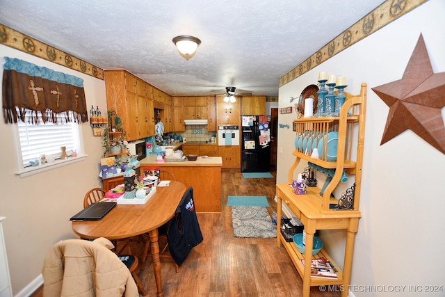 kitchen with black appliances, hardwood / wood-style flooring, decorative backsplash, ceiling fan, and a textured ceiling